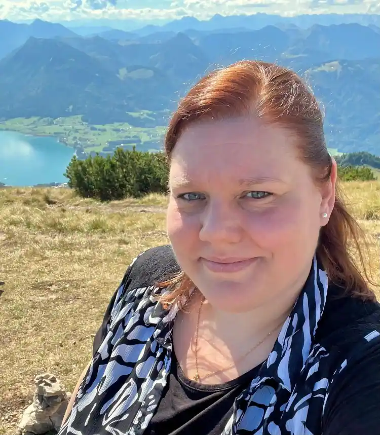 Christina, Gründerin von Human Design mit Herz, in der Natur mit Blick auf die Berge und einen See im Hintergrund